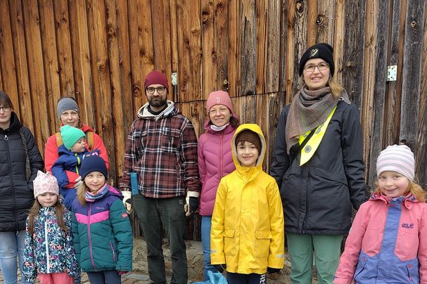 Erwachsene und Kinder in wetterfester Kleidung mit Müllsäcken im Vordergrund 