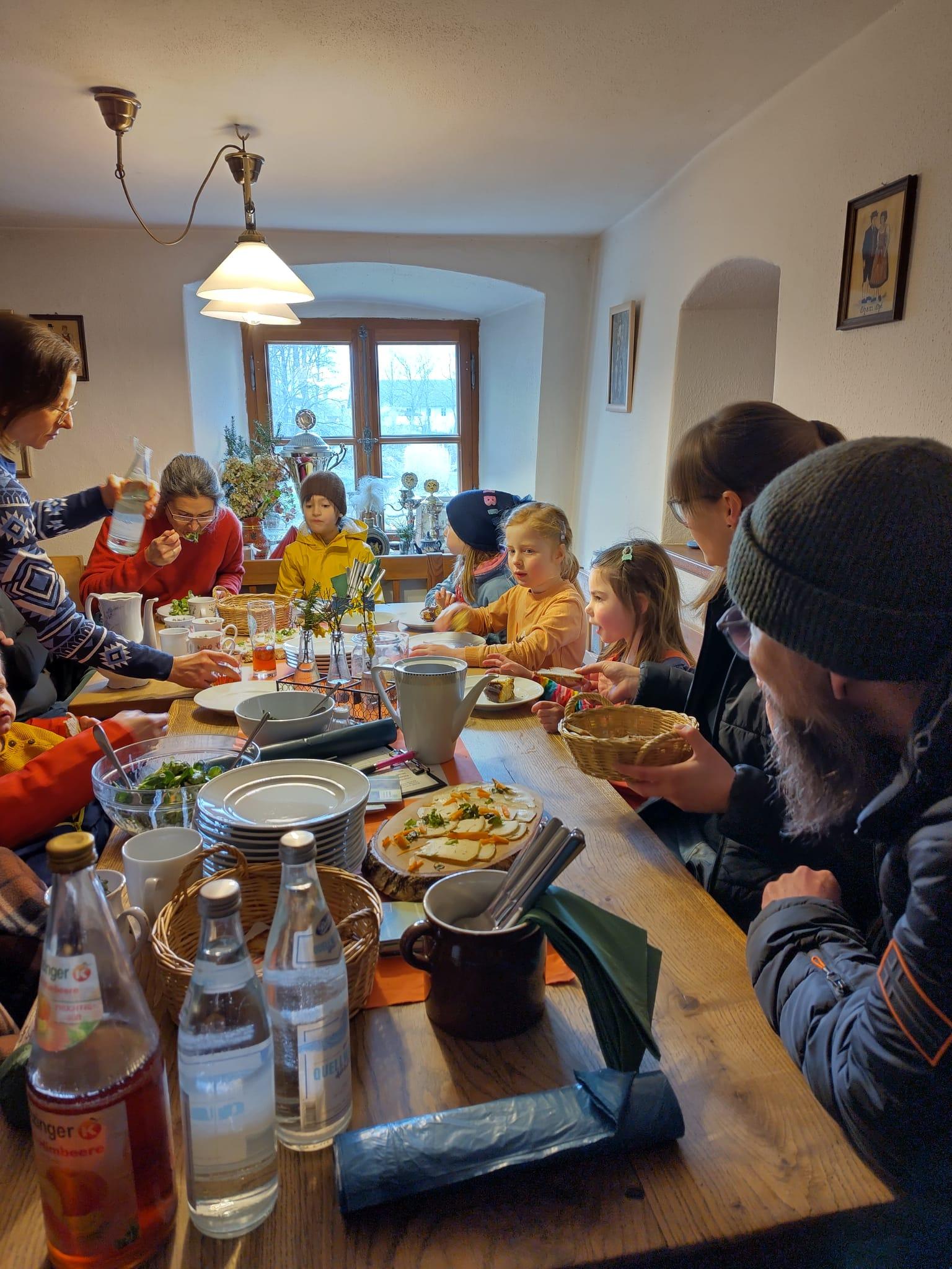 Kinder und Erwachsene sitzen um einen Tisch und essen